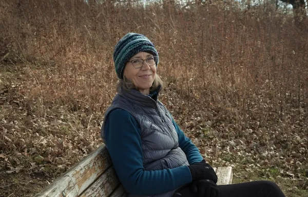 Susanne sitting outside in autumn on a wooden bench.