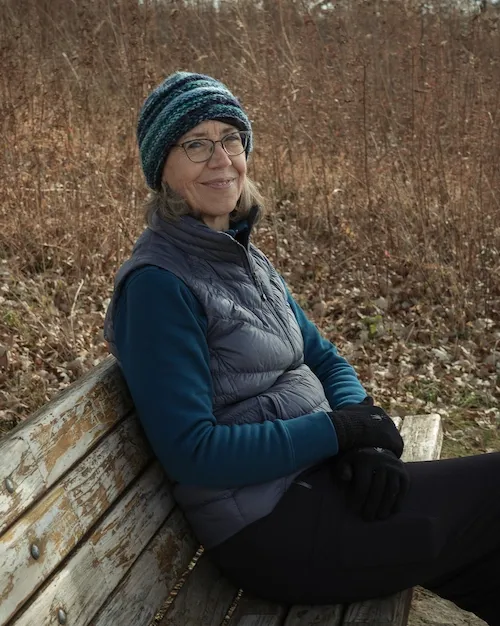 Susanne sitting outside in autumn on a wooden bench.